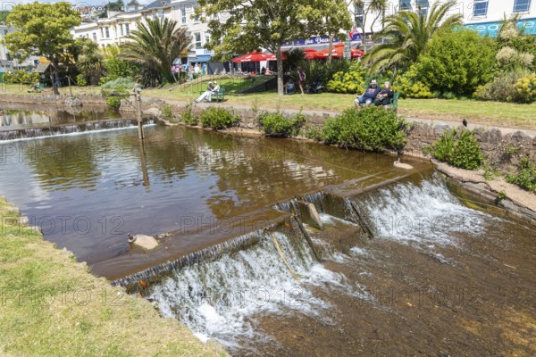 Dawlish Water river flowing through park gardens in town centre, Dawlish, south Devon, England, UK