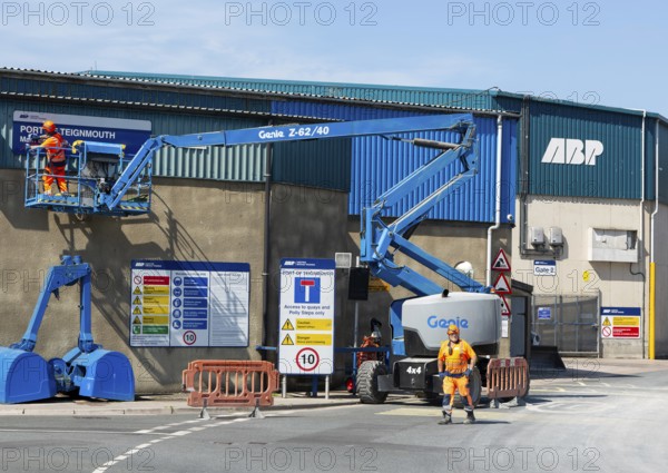 Man on cherry picker machinery cleaning sign, Port of Teignmouth, Teignmouth, south Devon, England,