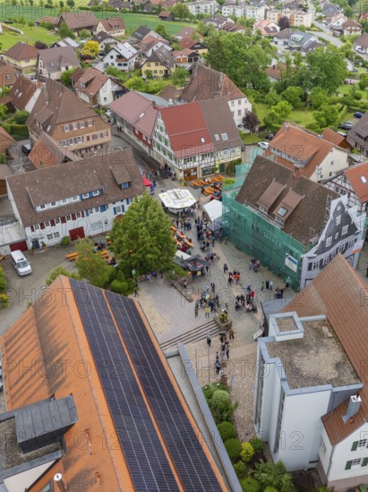 Aerial view of a village square with people and traditional buildings with tiled roofs, family