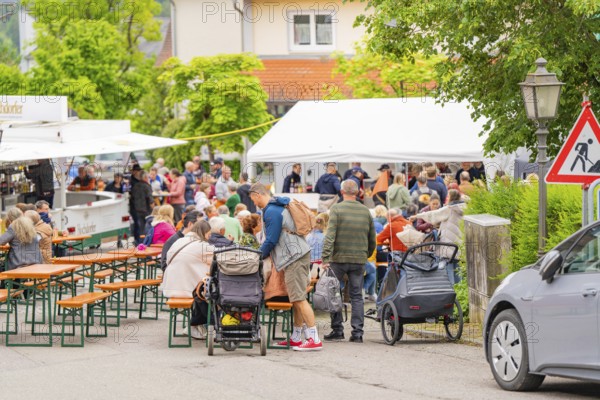 Lively street festival with many people at beer tent sets, cheerful and sociable atmosphere, family