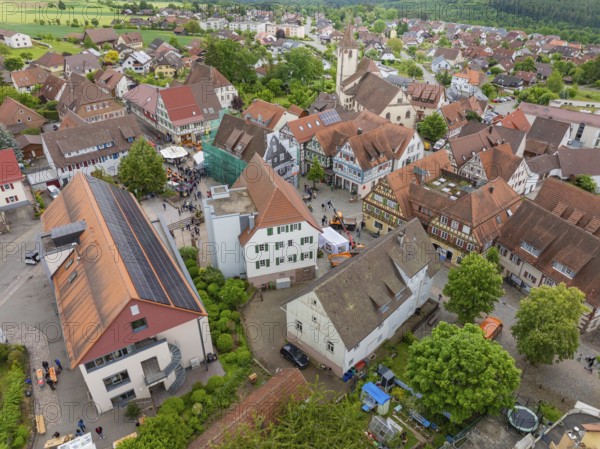 Aerial view of a village with historic architecture, numerous red roofs and a central church,