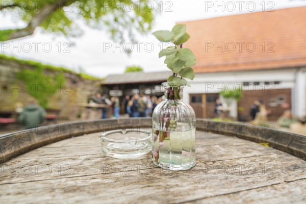 Wooden table with decorative glass bottle in a relaxed outdoor area at an event, family celebration