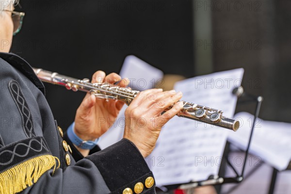 Musician playing the flute during a performance, in uniform with sheet music, family party in