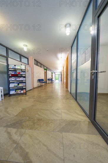 Long, modern hallway with glass doors, brochure rack and bright light, family party in Neubulach,