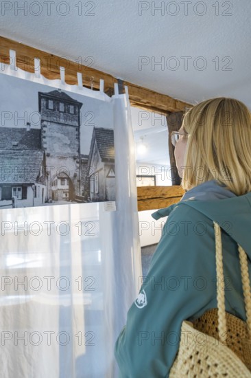 Woman looking at historical photograph in a room with wooden elements, family celebration in
