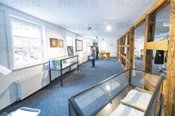 White modern exhibition space with works of art and few visitors, family party in Neubulach,