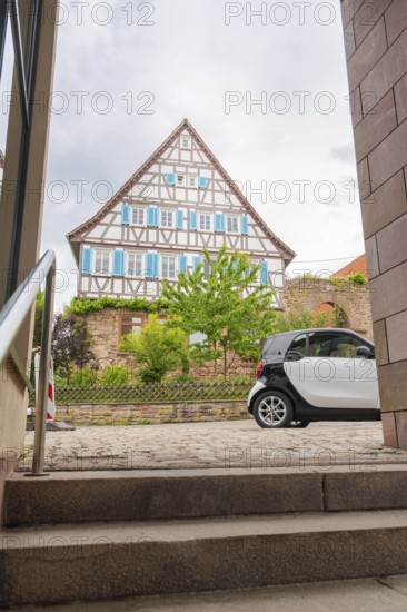 Traditional half-timbered house in the old town centre with a car in the foreground and steps,