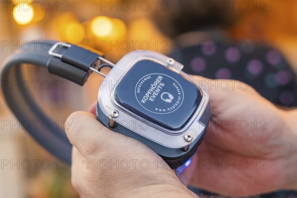 Advanced headphones are held in one hand and looked at, Calw railway station festival, Black
