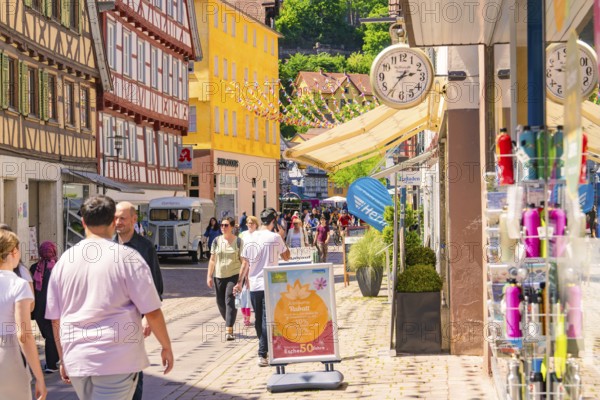 Lively street with half-timbered houses and shops, full of pedestrians on a sunny day, Calw railway