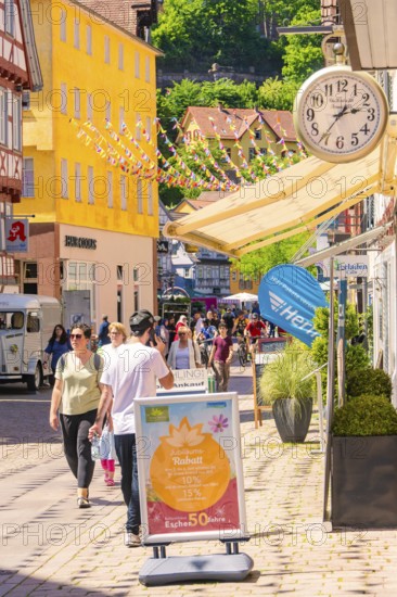 Lively shopping street with cheerful passers-by and colourful decorations on a sunny day, Calw