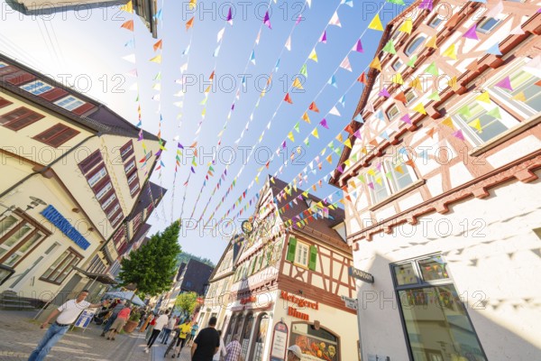 Colourful pennants span a picturesque street with half-timbered houses, Calw station festival,