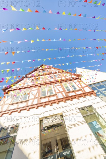 Half-timbered house decorated with colourful pennants under a clear blue sky, Calw station