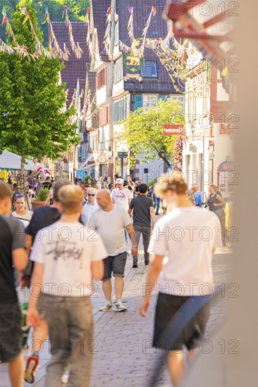 Lively city street full of people on a sunny day, Calw railway station festival, Black Forest,
