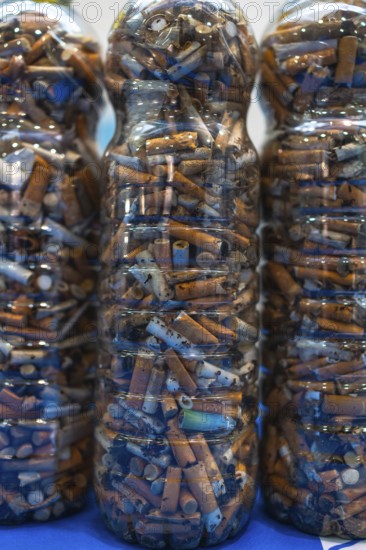 Plastic bottles filled with cigarette butts collected during cleanup efforts on a beach,