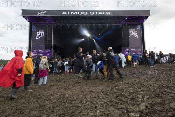 Festival visitors dance in the mud in front of the Atmos Stage at the Rock am Ring Festival on