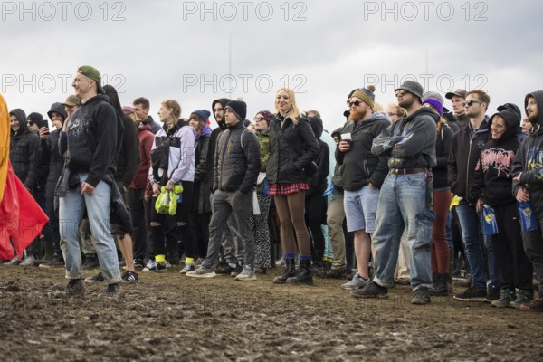 Festival-goers stand in the mud in front of the Atmos Stage at the Rock am Ring Festival on Sunday,