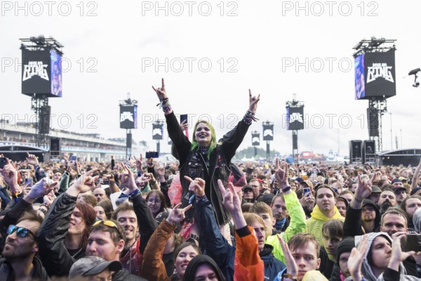 Festival visitor on shoulders with a French fries fork shaped like a hand at the Rock am Ring