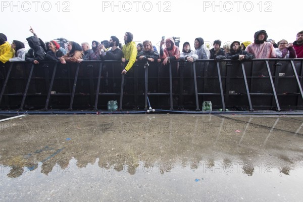 Festival visitors at the barrier are reflected after heavy rain at the Rock am Ring Festival on