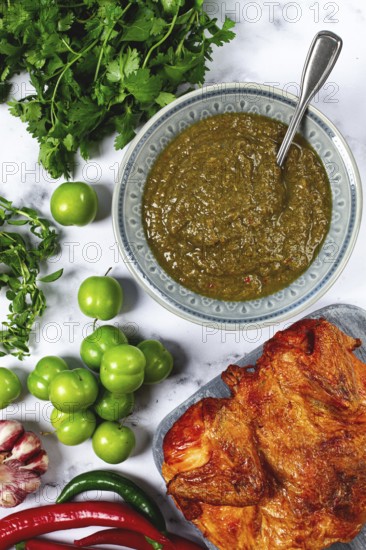 Tkemali sauce, made from green cherry plum, with ingredients on the table, tobacco chicken, top