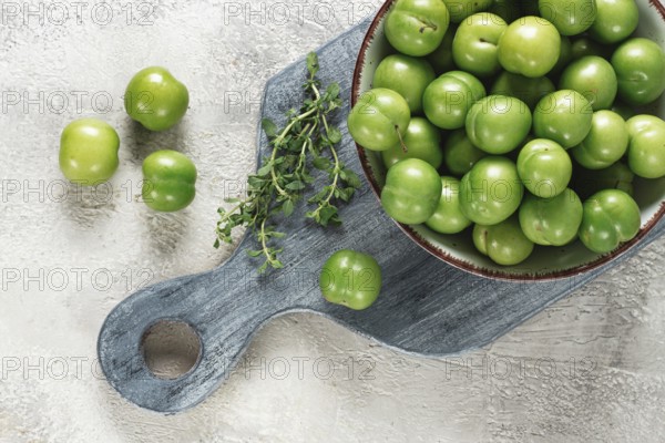 Tkemali, green cherry plum, in a bowl, on a gray table, top view, natural light, no people