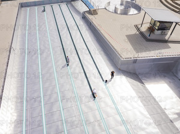 High-angle shot of a swimming pool under construction with workers, renovation of the swimming