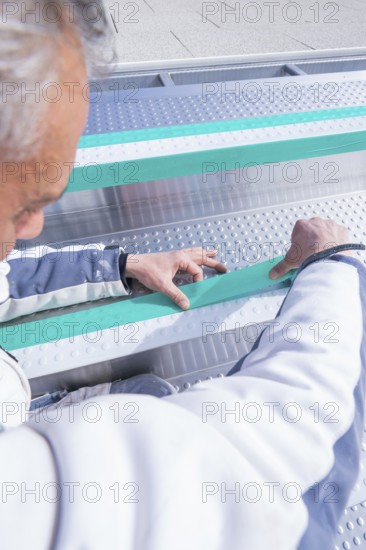Worker adjusts stripes in the swimming pool with his hands, renewal of the swimming lines, Calw