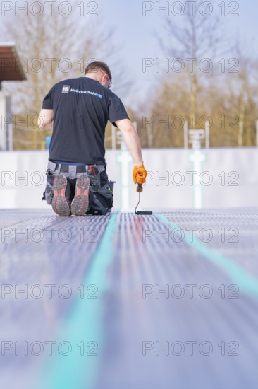 Rear view of a worker on a construction site applying strip paint with a roller, renovation of the