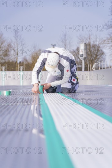 A worker on the construction site sticks a green tape along the floor, renewal of the swimming