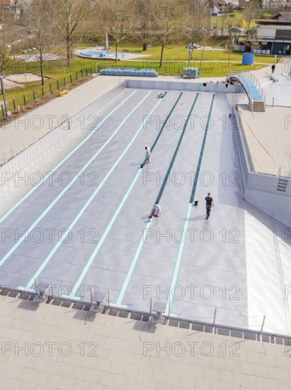 People working at an empty swimming pool in a green environment, renewal of the swimming lines,