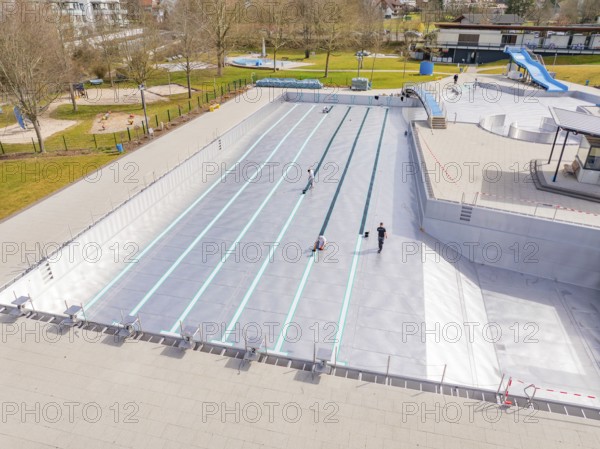 Swimming pool with workers and green surroundings in the distance, renewal of the swimming lines,