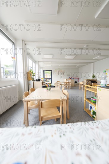 Bright kindergarten room with wooden furniture and large windows, transitional containerised