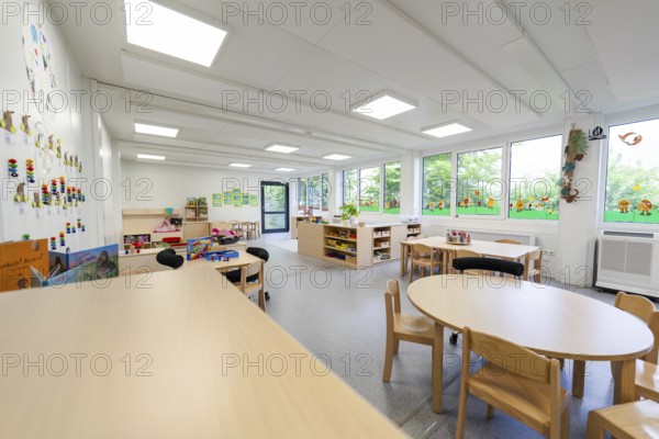Large, bright nursery room with windows, tables and chairs, wall decorations, transitional