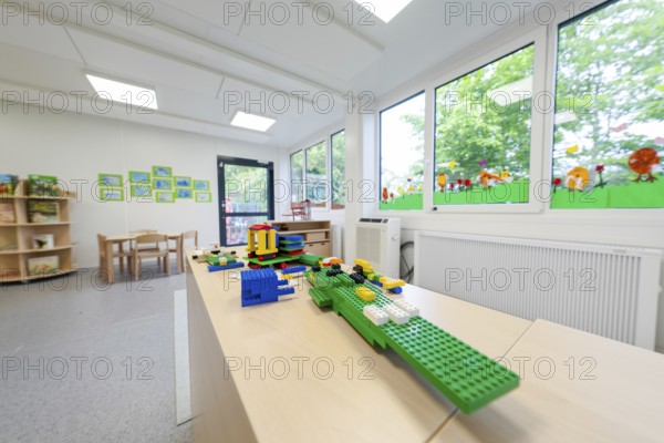 Kindergarten room with building blocks on a table, large windows with a view of the countryside,