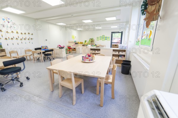 Learning room with tables and chairs, surrounded by bright windows and decorations, transitional