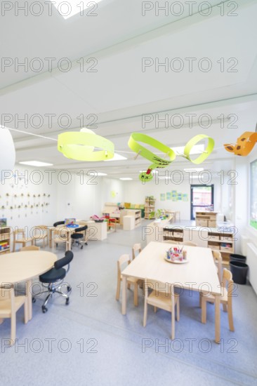 Open school classroom with paper artwork and wooden furniture, transitional containerised daycare