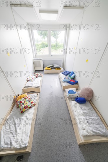Overview of a dormitory for children with beds, lit by windows, transitional containerised daycare