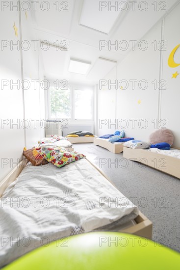 Sleeping room for children with beds and colourful cushions, flooded with light and quiet,