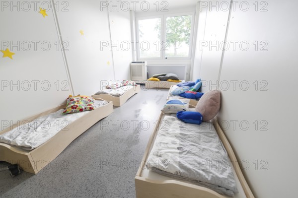A bright bedroom with several small beds and colourful cushions, transitional daycare centre in