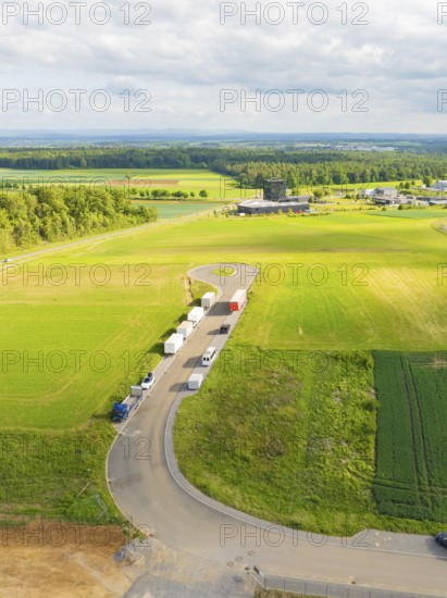 Country road with parked vehicles and extensive fields in a rural setting, ING Park development
