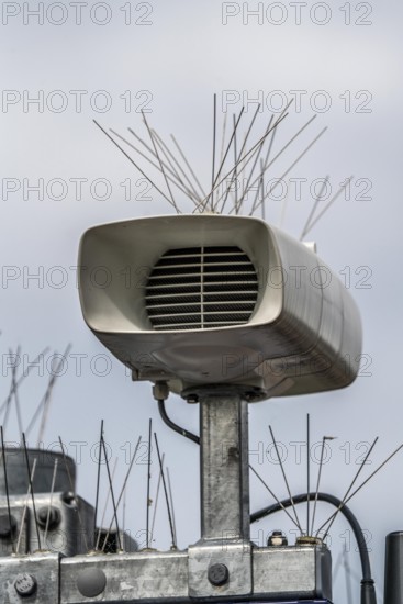 Loudspeakers on a scoreboard, at a railway station, studded with thin wires against birds, pigeons,