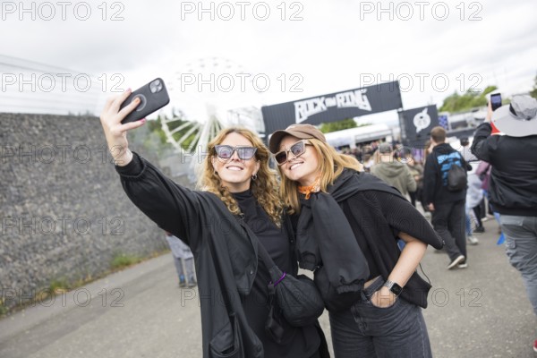 Two festival visitors take a photo of themselves in front of a container with the Rock am Ring logo