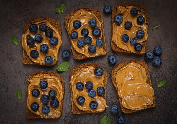 Rye bread with peanut paste and fresh blueberries, top view, no people