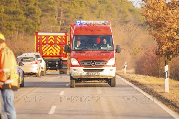 Two fire engines drive on a country road, road markings visible, fire brigade exercise on the