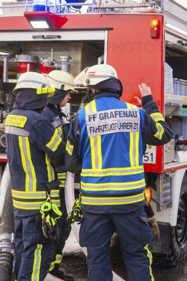 Firefighters are preparing to carry out extinguishing measures on a red vehicle, fire brigade