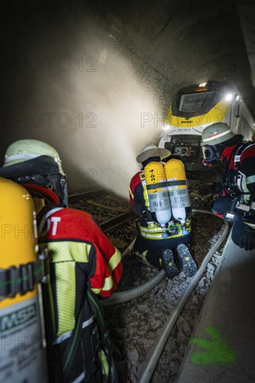 Firefighters with respirators extinguish a fire in a tunnel using water hoses, fire brigade