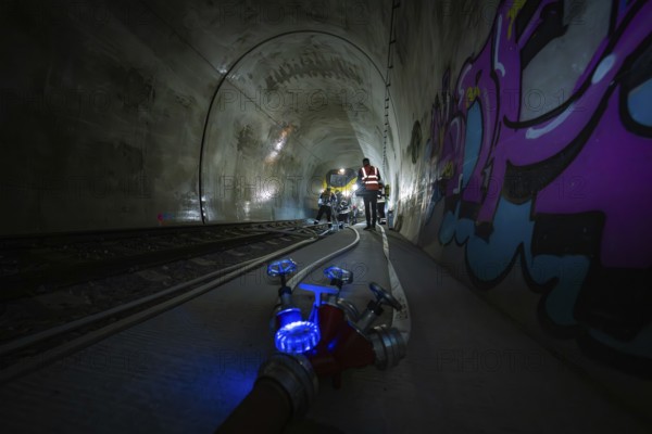 People work in the dark tunnel. Technical equipment and colorful graffiti on the walls, fire