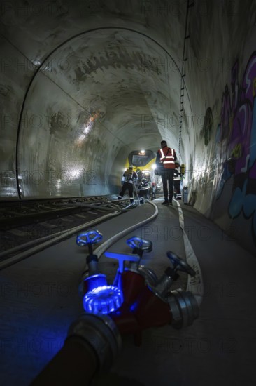 Workers in the dark railroad tunnel. Lighting and technical equipment are visible, fire department