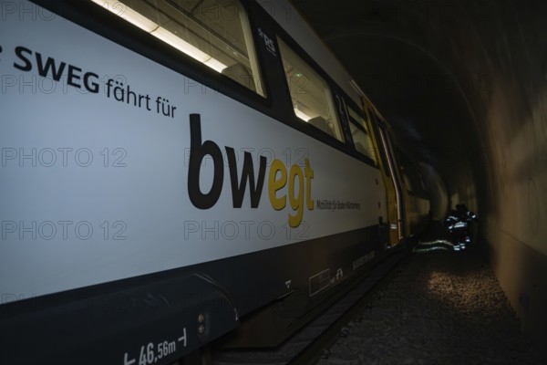 Train in a tunnel with lettering on the side in dark surroundings, fire department exercise on the