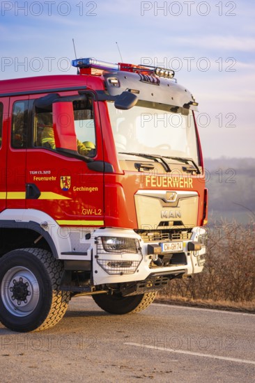 Red fire engine on a street in sunshine, fire brigade exercise on the Hermann Hesse railway,
