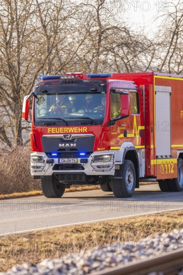 Red fire truck is driving on a country road. Barren winter landscape in the background, fire